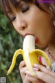 A woman is eating a banana with her mouth open.