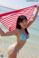 A woman in a blue bikini holding a red and white striped towel.