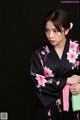 A woman wearing a black kimono with pink flowers on it.