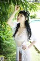 A woman in a white dress posing by a pool.