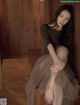 A woman sitting on top of a wooden bench.