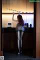 A woman standing in front of a bar in a room.