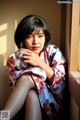 A woman in a kimono sitting on a window sill.