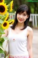 A woman standing next to a bunch of sunflowers.