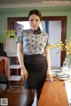 A woman standing in front of a table with a vase of flowers.